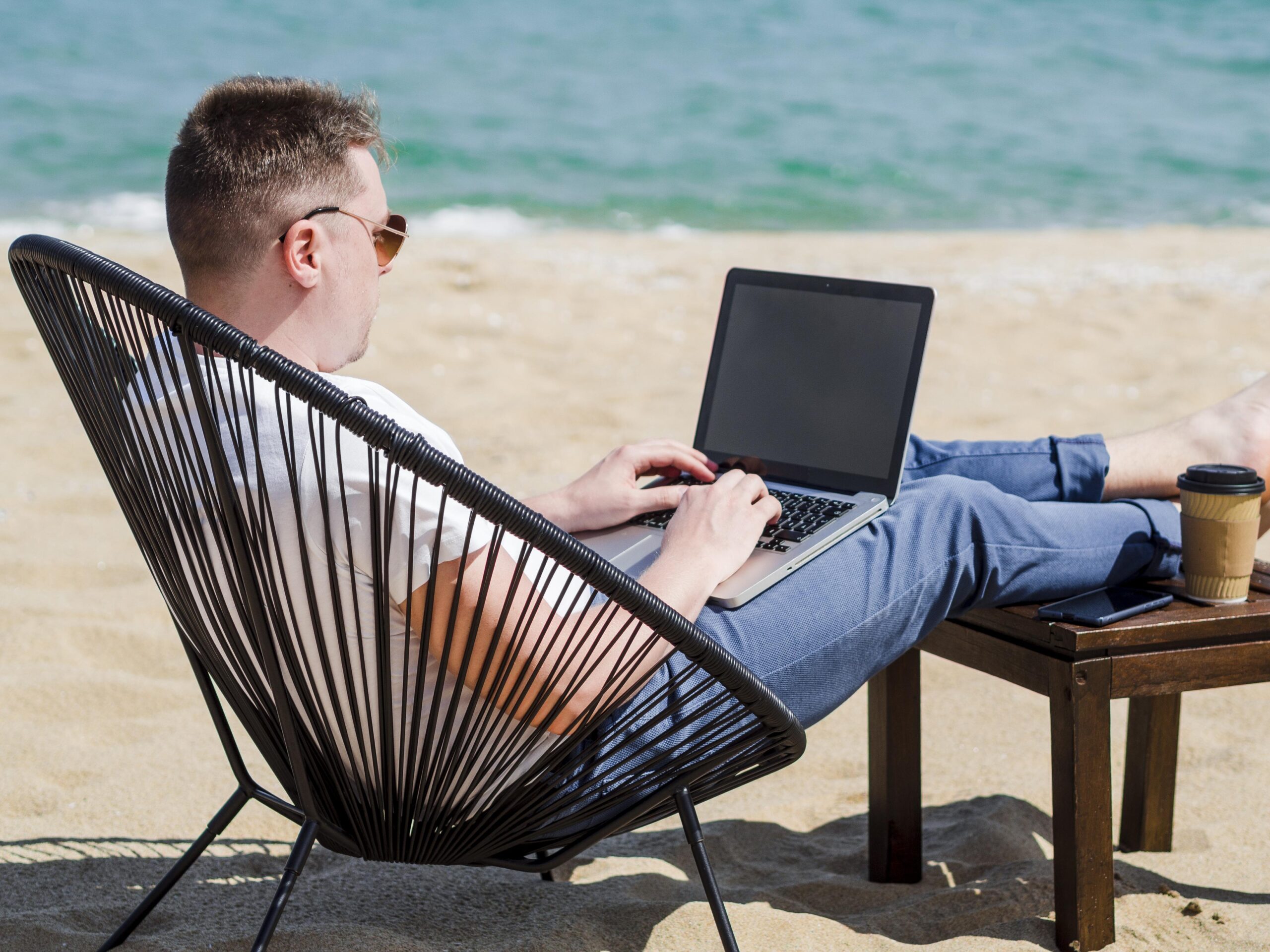 side-view-woman-working-laptop-beach